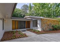 Charming exterior with a stone accent wall, painted brick, and flower beds leading to the front door at 4717 Westhampton Dr, Tucker, GA 30084