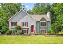 Charming two-story home with a well-manicured lawn, stone accents, red shutters and a bright red front door at 4638 Arrow Wind Dr, Powder Springs, GA 30127