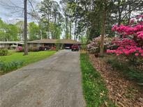 Charming single-story home featuring a long driveway and colorful landscaping at 2564 Wren Nw Ave, Duluth, GA 30096