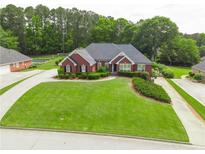 Charming brick home featuring lush green lawn, mature landscaping, and inviting entrance at 811 Ivy Ridge Dr, Loganville, GA 30052