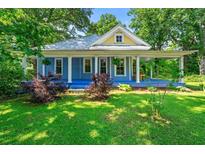 Charming blue home featuring a metal roof, a welcoming front porch, and lush landscaping at 7550 Fielder Rd, Jonesboro, GA 30236