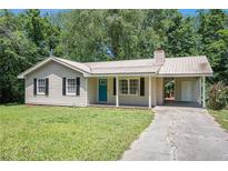 Charming one-story home with a metal roof, teal door, and well-maintained front yard at 10312 Waterford Ne Rd, Covington, GA 30014