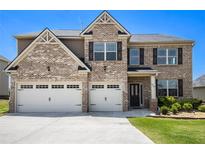 Charming two-story brick home featuring a manicured lawn and a convenient two-car garage at 320 Conley Ave, Hampton, GA 30228