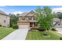 Charming two-story home with a manicured lawn, a two-car garage, and stone accents at 1955 Piedmont Cove Ln, Cumming, GA 30040