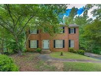Traditional two-story brick home featuring a lush front yard with mature trees and black shutters at 1201 Justin Ln, Lithonia, GA 30058