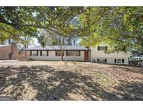 Charming one-story home featuring brick accents, well-maintained landscaping and a bright red front door at 1887 King Charles Sw Rd, Atlanta, GA 30331
