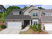 Charming townhome features a two-car garage, brick facade, and manicured landscaping at 2706 Park Land Ln, Snellville, GA 30078