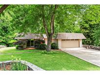 Charming home featuring lush landscaping, stone accents, and a large, shady tree in the front yard at 1075 Winding Branch Ln, Atlanta, GA 30338
