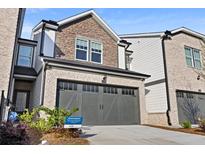 Charming townhome showcasing a gray two-car garage, brick, and siding for a modern aesthetic at 2440 Rocky City Ln, Snellville, GA 30078
