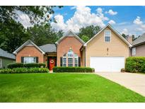 Charming home with a well-manicured lawn, brick accents, a two-car garage, and a welcoming red front door at 9013 Aldbury Dr, Locust Grove, GA 30248