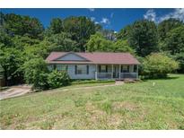 Charming single-story home with a cozy front porch and a well-manicured lawn surrounded by lush trees at 501 Textbook Ct, Lawrenceville, GA 30044