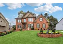 Stunning two-story brick home featuring manicured lawn and inviting front yard with beautiful garden and water feature at 1932 River Crest Way, Lawrenceville, GA 30045