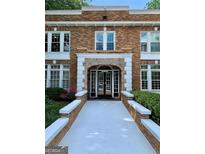 Brick building exterior with white accents, arched entryway, and manicured landscaping at 242 12Th Ne St # 1A, Atlanta, GA 30309