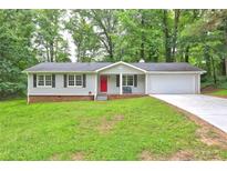 Charming single-story home featuring a red front door, attached garage, and a well-manicured lawn at 3963 Holland Ct, Douglasville, GA 30135