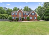 Beautiful two-story brick home with blue shutters and a well-manicured front yard with mature trees at 129 Crown Walk, Mcdonough, GA 30253