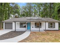 Charming single-story home boasts a new roof, solar panels, white siding, and a pop of color from the bright blue front door at 3216 Montheath Ct, Duluth, GA 30096