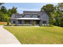 Stunning gray two-story modern farmhouse with a white porch and beautifully landscaped front yard at 157 Palisade Ne Dr, Rydal, GA 30171