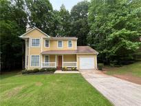 Charming yellow two-story home with a well-manicured lawn and mature trees at 5464 Fox Haven Trl, Stone Mountain, GA 30088