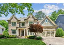 Charming two-story brick home featuring an attached two-car garage and a well-manicured front yard at 1320 Magnolia Park Cir, Cumming, GA 30040