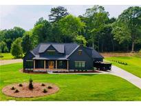 Beautiful two-story home boasts a black exterior, spacious yard and wooded backdrop at 1111 Lake Varner Dr, Covington, GA 30014