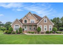 Charming two-story brick and stucco home with a manicured lawn and established landscaping at 127 Courts Of Hampton, Hampton, GA 30228