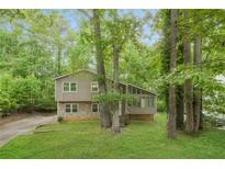 Charming home with a stone foundation and a lush green lawn surrounded by mature trees at 8607 Wood Springs Ct, Douglasville, GA 30135