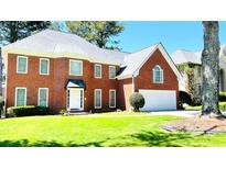 Charming brick home featuring a well-manicured lawn and attached two-car garage with a lovely tree in the front yard at 5633 Southland Dr, Stone Mountain, GA 30087