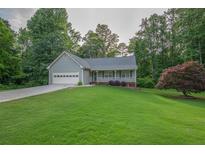 Charming single-story home boasts a well-manicured lawn, attached garage, and inviting front porch at 399 Towler Drs, Loganville, GA 30052