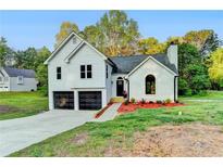 Charming two-story home with a well-manicured lawn, black garage doors, and inviting front entrance at 545 Woodrow Dr, Lawrenceville, GA 30043