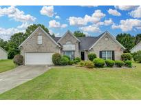 Charming single-Gathering home with a lush green lawn, well-manicured bushes, and a two-car garage at 3865 Portico Run Dr, Buford, GA 30519