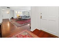 Inviting living room featuring hardwood floors, a large mirror, and a stylish red patterned rug at 52 Chaumont Nw Sq, Atlanta, GA 30327