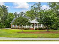 Charming brick home with a welcoming front porch and well-manicured lawn and mature trees at 1253 Oakwood Pl, Loganville, GA 30052
