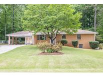 Charming brick home featuring mature landscaping, a welcoming covered carport, and a well-manicured lawn at 519 Beaver Ruin Nw Way, Lilburn, GA 30047