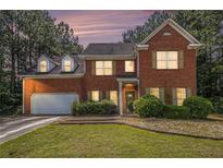 Charming two-story brick home with well-manicured lawn, mature trees, and an attached two-car garage at 2451 Broad River Pl, Ellenwood, GA 30294
