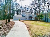 Charming two-story home featuring a stone accent wall, light gray siding, and a long driveway nestled in a wooded area at 5419 S Lake Dr, Douglasville, GA 30135