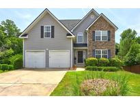 Charming two-story home featuring stone accents, a two-car garage, and a well-manicured front yard at 347 Cobblestone Court, Hampton, GA 30228