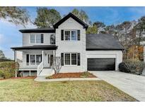Charming two-story home with white brick, black shutters, an attached garage and a landscaped front yard at 1285 Cedar Brook Dr, Lawrenceville, GA 30043