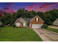 Charming brick home with a manicured front lawn and a two-car garage nestled among lush trees at 1290 Silverstone Trl, Jonesboro, GA 30238