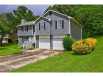 Split-level home featuring a two-car garage and front yard with shrubs and lawn at 4090 Mark Todd Ct, Hoschton, GA 30548