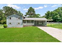 Charming home featuring a well-manicured lawn, carport, and classic architectural details at 320 Edna Dr, Stockbridge, GA 30281
