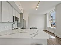 Modern kitchen with white cabinets, stainless steel appliances, and a large marble countertop island at 57 Forsyth Nw St # 14B, Atlanta, GA 30303
