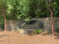 Stone sign at Riverwalk, a private community of River Townhomes with trees and greenery at 248 Riverview Trl, Roswell, GA 30075