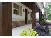 Covered porch with stone accents, wooden beams, and well-maintained landscaping enhances curb appeal at 3007 Holly St, Canton, GA 30115