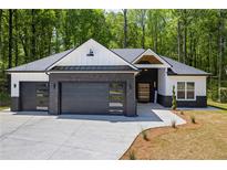 Charming home showcasing a black brick facade, modern garage doors and a well-manicured lawn at 632 Hunters Cove Ln., Loganville, GA 30052