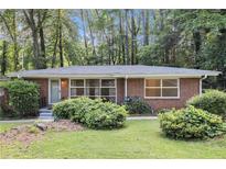 Charming brick home with large windows and a well-maintained lawn and mature landscaping at 1461 Alverado Way, Decatur, GA 30032