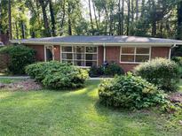 Charming brick home featuring large windows and lush landscaping in a serene, wooded setting at 1461 Alverado Way, Decatur, GA 30032
