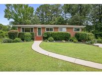 Charming brick home with a well-manicured lawn, beautiful shrubs, and a welcoming walkway to the front door at 388 Talcott Nw Cir, Marietta, GA 30064