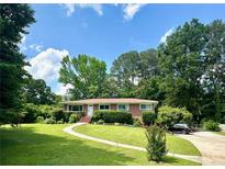 Charming one-story brick home with a well-manicured front lawn, a curved walkway, and mature landscaping at 388 Talcott Nw Cir, Marietta, GA 30064