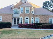 Charming brick home featuring a manicured lawn, blooming bushes, and elegant arched windows enhancing its curb appeal at 5430 Lemoyne Sw Dr, Atlanta, GA 30331
