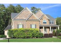 Charming two-story home with a brick and stone facade, well-manicured lawn and mature landscaping at 6570 Canyon Cv, Cumming, GA 30028